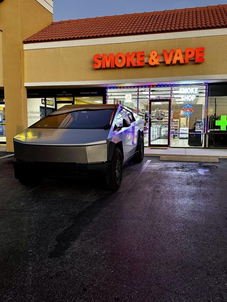 Cloud Factory Smoke and Vape storefront at night with Cybertruck parked outside